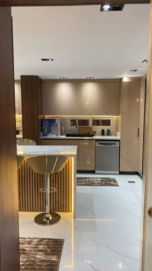 Eine moderne Küche mit Marmorarbeitsplatte, einem eingebauten Geschirrspüler und einer Bar mit einem Hocker.