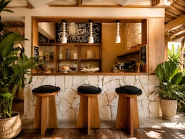 Un café rústico con pared de piedra, taburetes de madera y una pizarra.