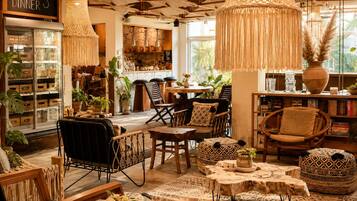 Un interior acogedor con comedor, mobiliario de mimbre y un letrero que anuncia servicio de brunch y cena.