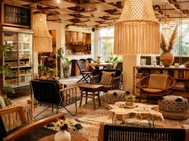Een gezellig interieur met een eetgedeelte, rieten meubels en een bord dat brunches en diners aangekondigt.