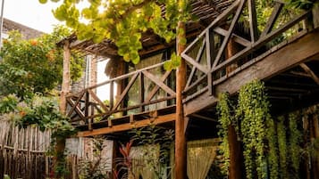 Una estructura de madera con techo, rodeada de abundante follaje y plantas.