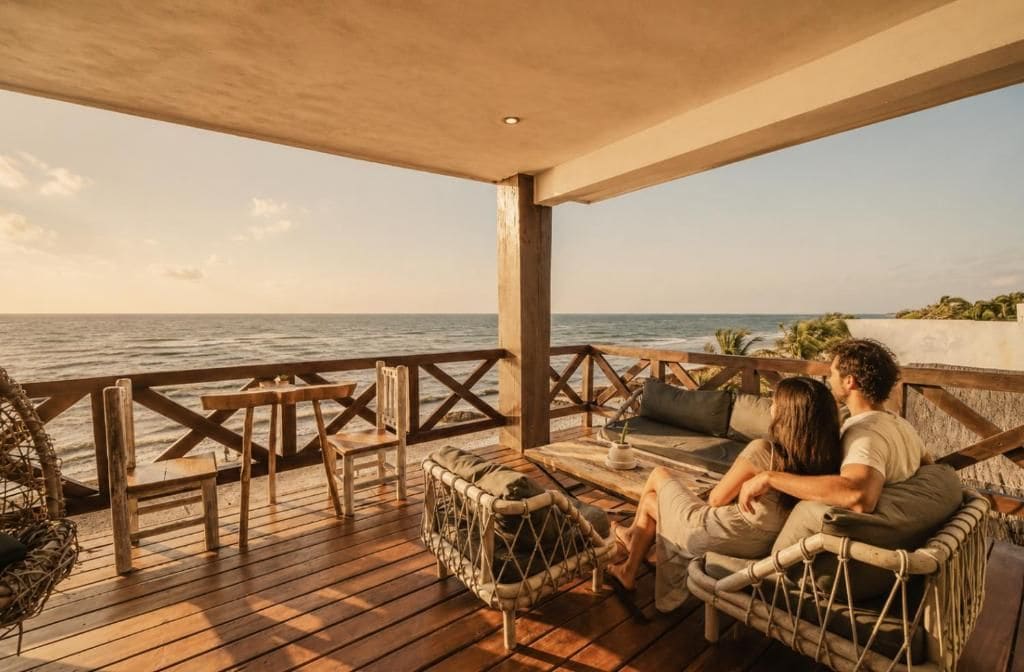 Una terraza de madera con muebles de mimbre y vista al mar.
