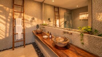 Un baño con tocador de madera, dos lavamanos, un espejo grande y zona de ducha.