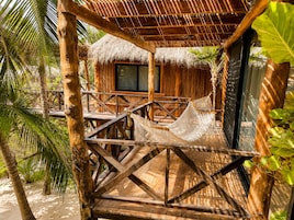 Una estructura de madera con techo de paja, una hamaca y una ventana.