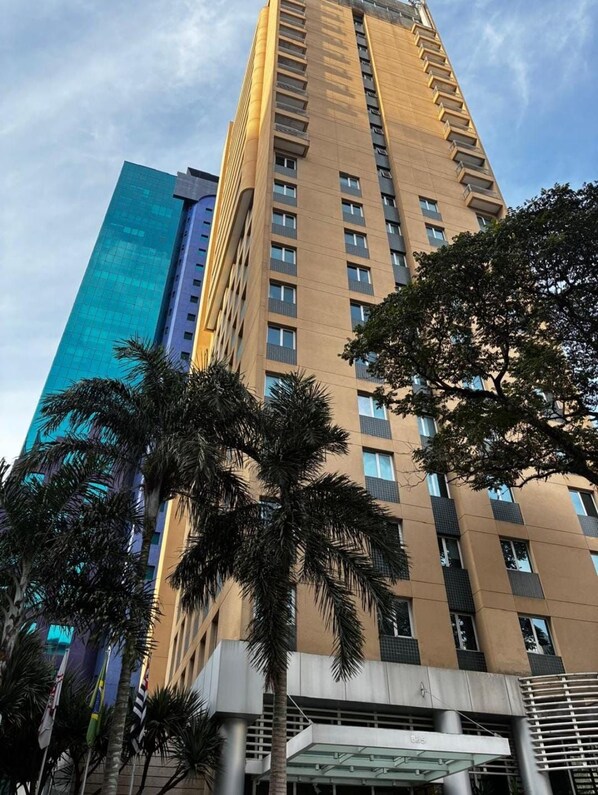 A tall building with multiple floors and balconies, surrounded by palm trees and a clear sky. - Vrbo Property (São Paulo)