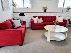 A living room with two red sofas, a white coffee table, and a lamp.