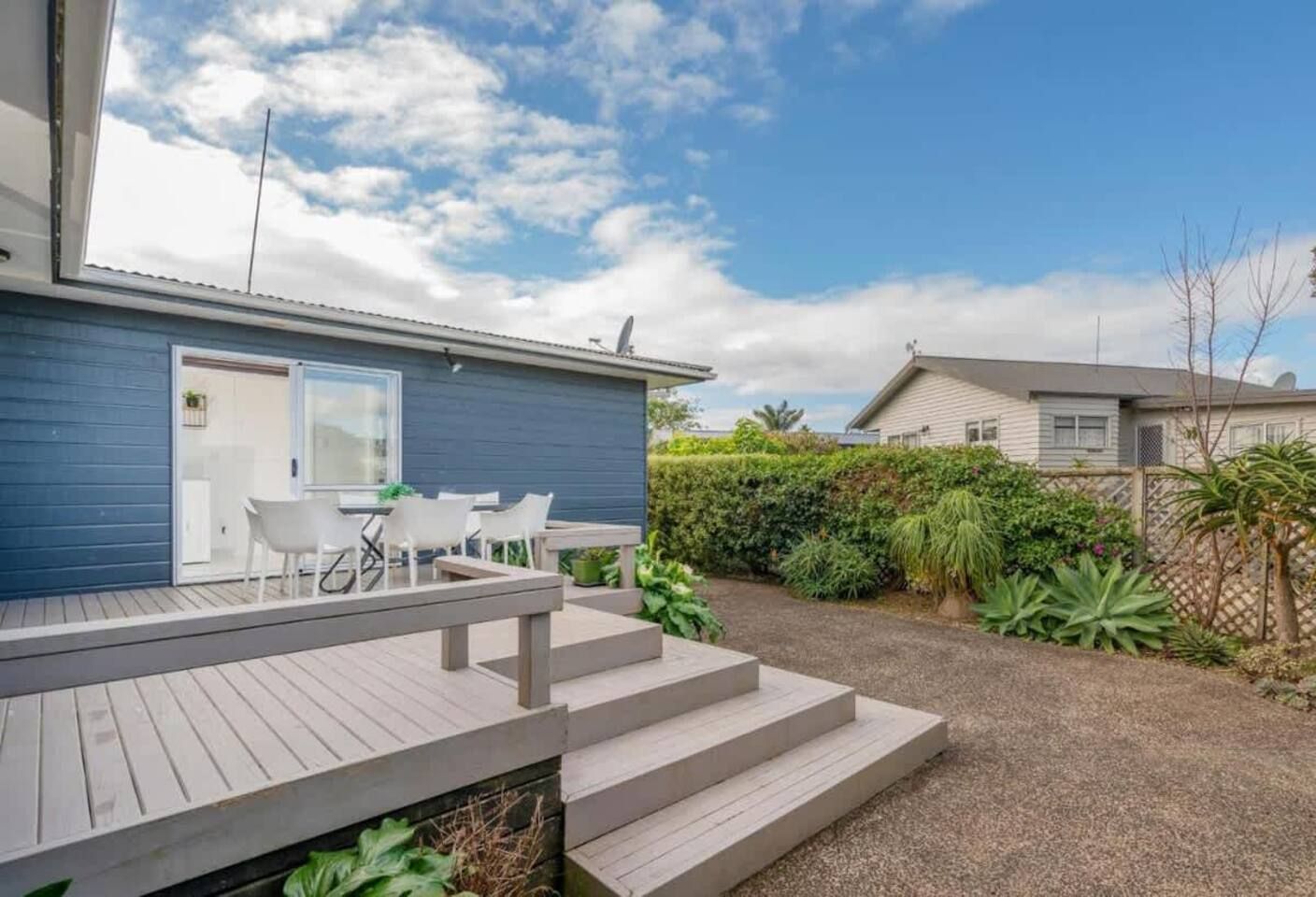 Ein Wohnhaus mit Terrasse, Sitzgelegenheit im Freien und einem angelegten Garten.