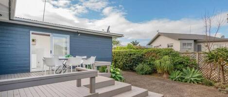 Une propriété résidentielle dotée d’une terrasse, d’un espace salon extérieur et d’un jardin aménagé.