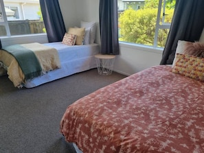A bedroom with two beds, a small round table, and a window with curtains.