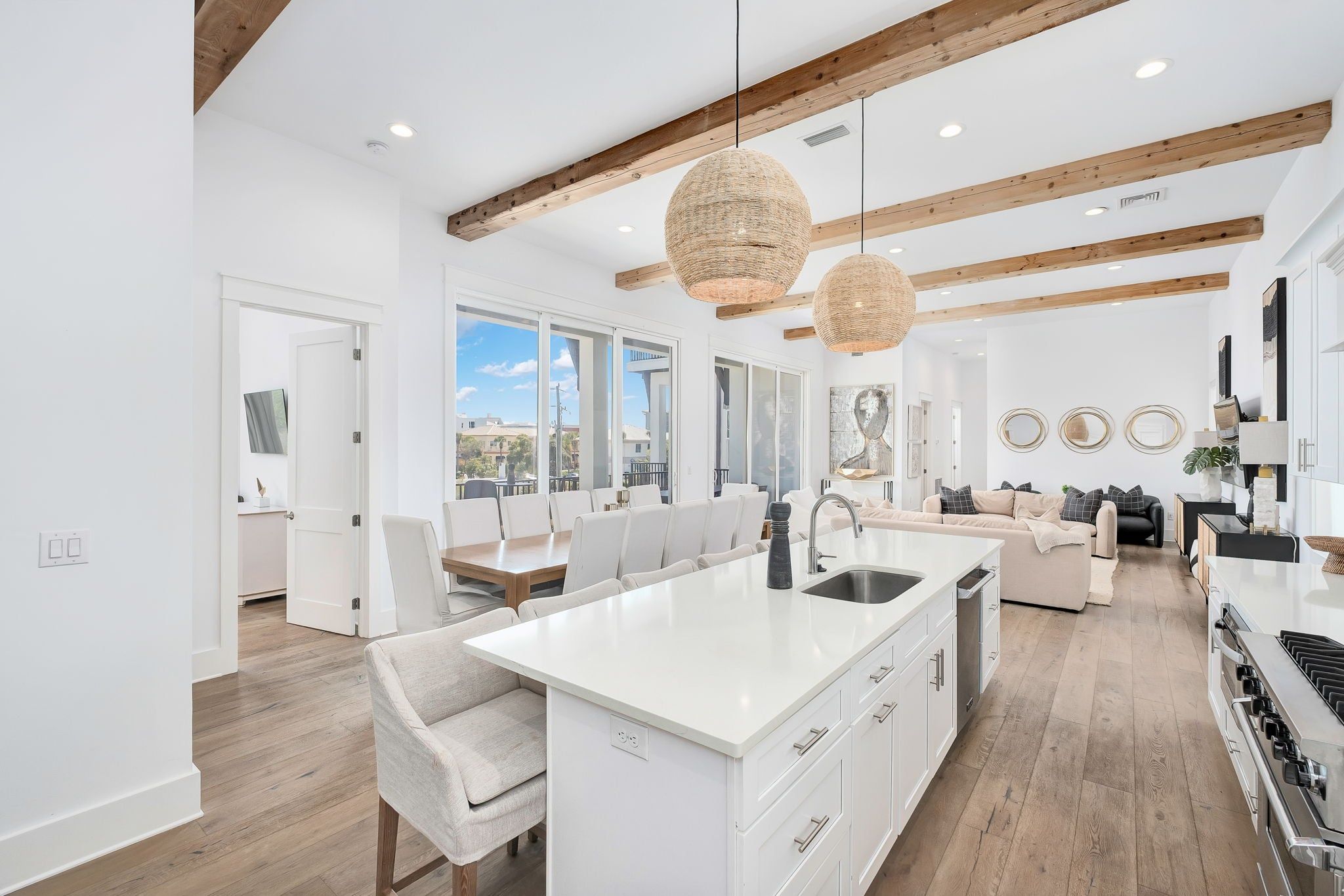 A modern kitchen with white cabinetry, a central island, and a dining area with white chairs.
