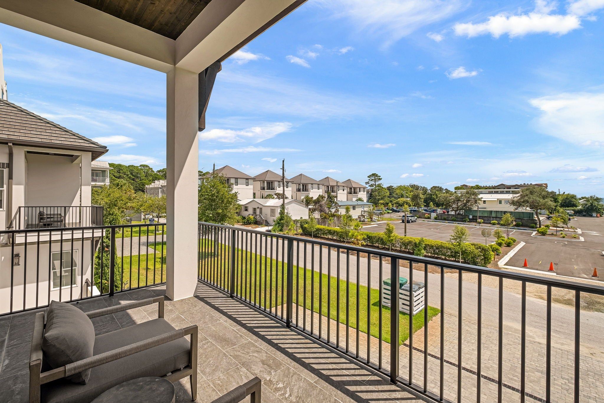 A balcony with a view of a residential area, including houses and a parking lot.