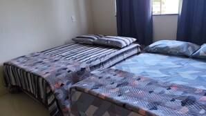 A room with two beds, a window with curtains, and an air conditioning unit. - Casa Brisa De Arraial (Porto Seguro)