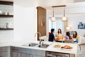 A modern kitchen with a central island, stainless steel appliances, and a dining area with a table and chairs.