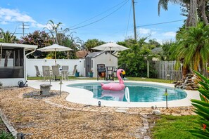 Un pati amb piscina, un flotsam de flamenc, mobles de terrassa i una zona d'estar coberta.