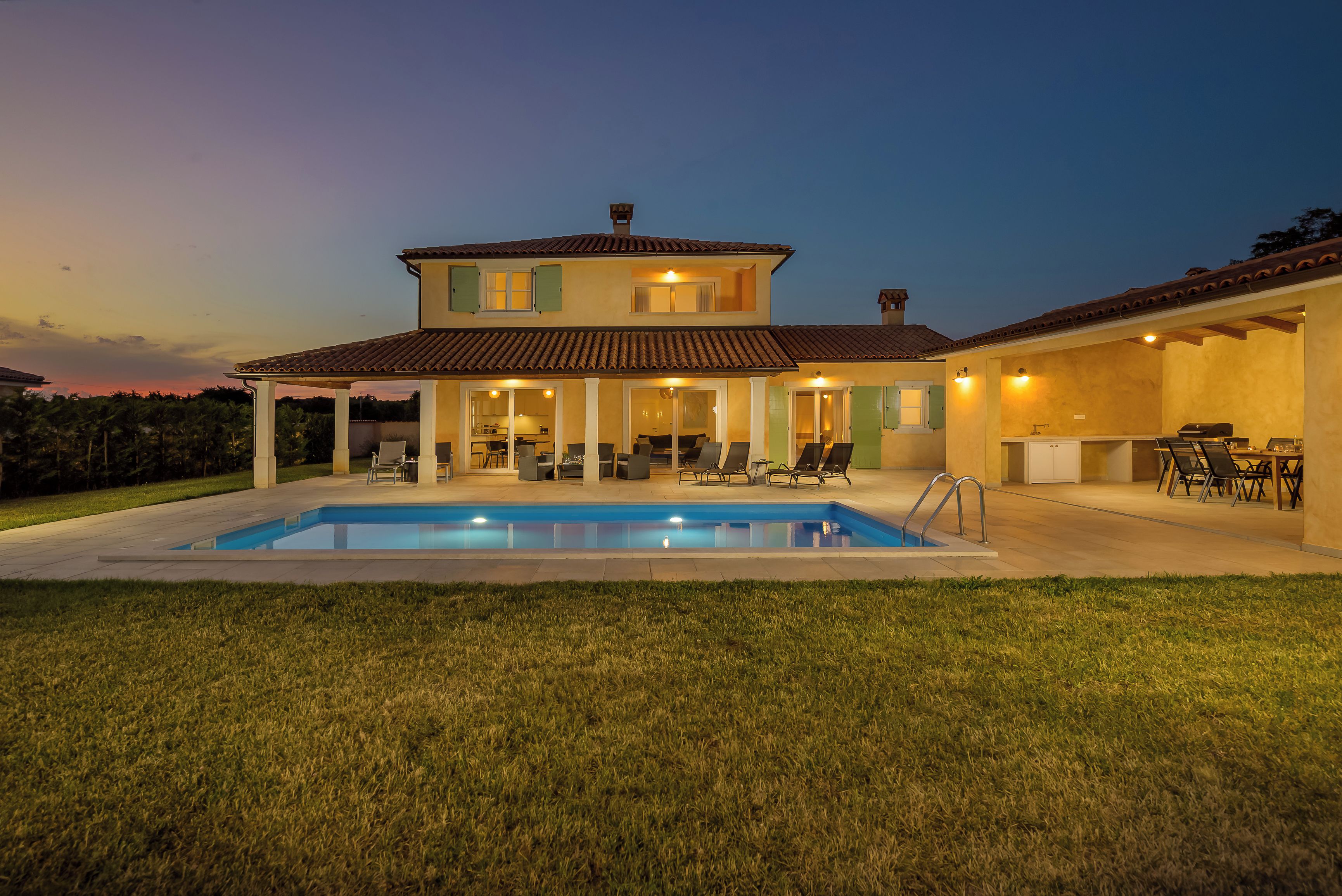 A two-story house with a swimming pool, outdoor seating, and a patio area.