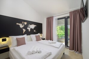 Ein Hotelzimmer mit einem großen Bett, einer Weltkarte an der Wand und einem Balkon mit Vorhängen.