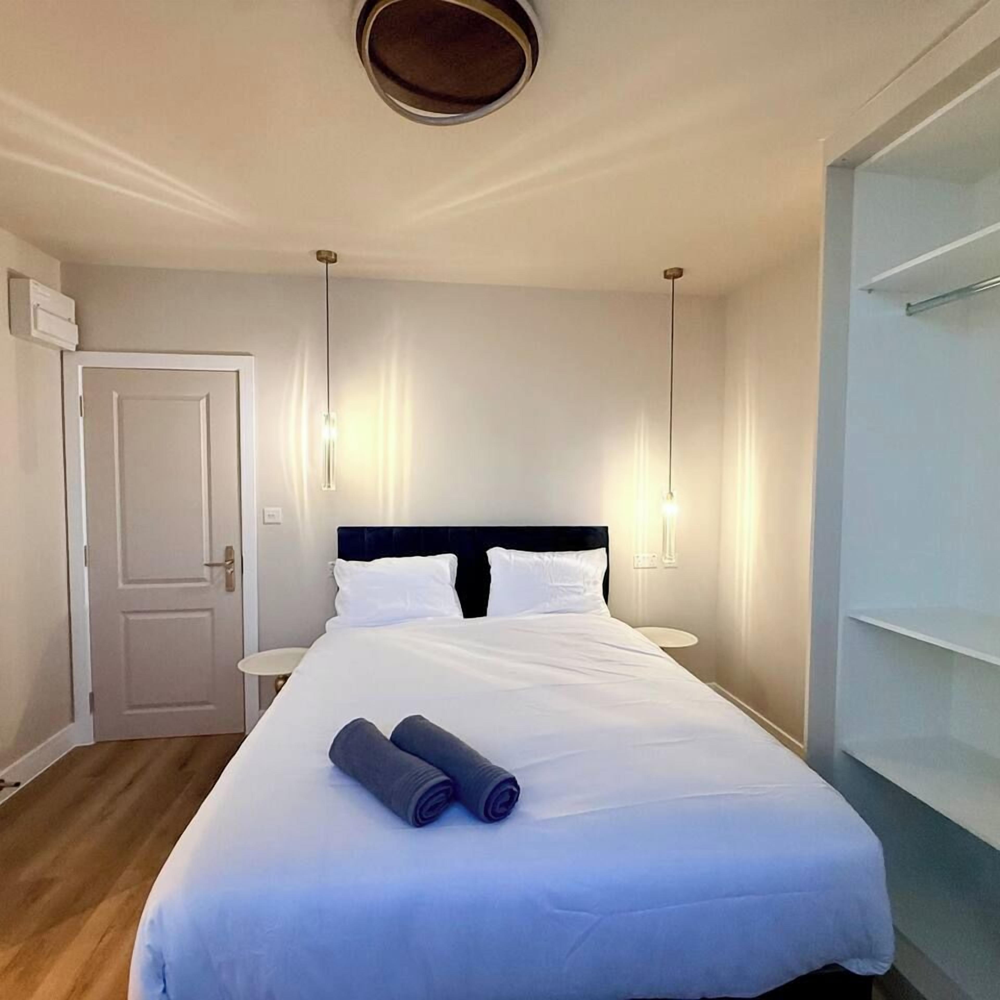 Una habitación de hotel con cama, mesitas de noche, una puerta y un armario.