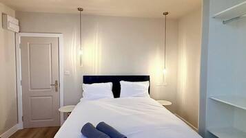 Una habitación de hotel con cama, mesitas de noche, una puerta y un armario.