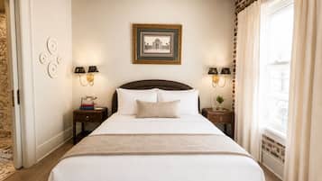 Una habitación de hotel con una cama grande, dos mesitas de noche con lámparas, un cuadro en la pared y una ventana con cortinas.