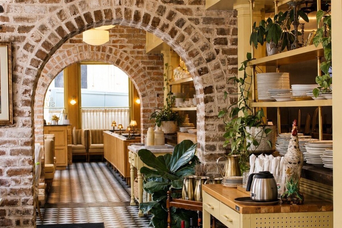 Un restaurante con paredes de ladrillo, suelo a cuadros y lámparas colgantes.