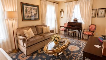 Una sala de estar con sofá, mesa de centro, piano y una silla.
