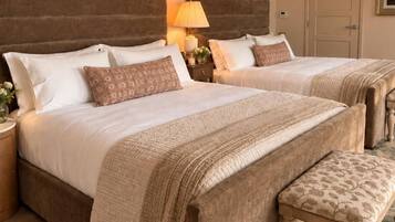A double bed with a headboard, a bedside table, a lamp, and a bench.