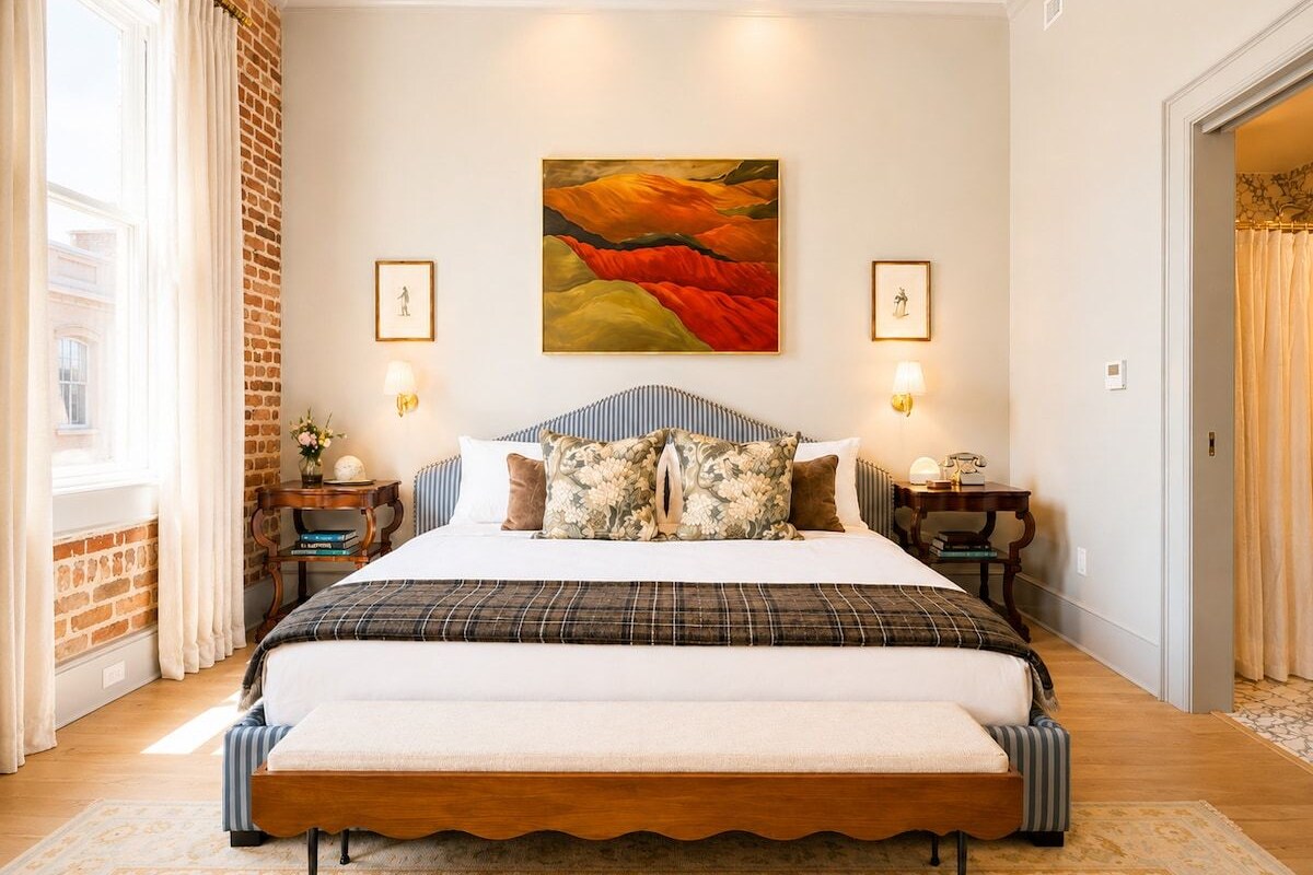 Un dormitorio amplio con una cama grande, una pared de ladrillo y un cuadro sobre la cama.