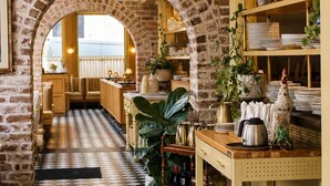 Un ristorante con parete in mattoni, pavimento a scacchi e lampade a sospensione.