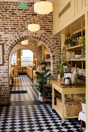 En restaurang med en vägg av tegelsten, ett rutmönstrat golv och hängande lampor.