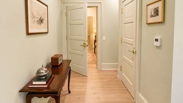 Un pasillo con una mesa de madera, libros, una radio antigua y cuadros en las paredes.