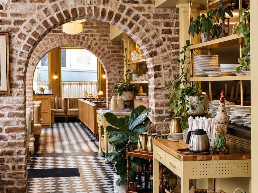 Un restaurant amb parets de maó, sòl de pissos i llums penjants.
