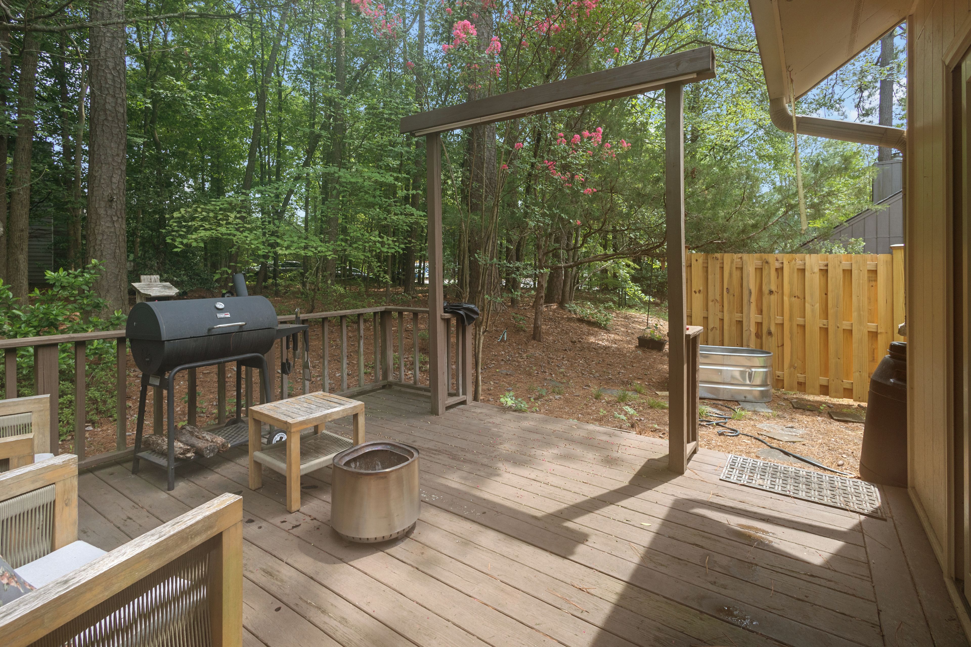 A covered outdoor deck with a grill, a table, and a bench.