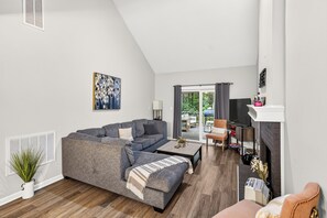 A modern living room with a grey sectional sofa, a coffee table, a TV, and a fireplace.