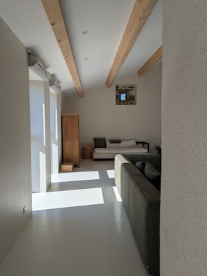 A modern interior with a wooden ceiling, a sofa, a cabinet, and a small window. - L'Atelier - Maison avec piscine face au volcan (Saint-Just-près-Brioude)