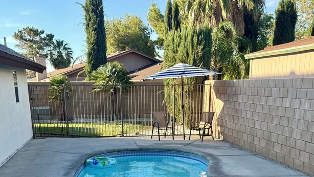 Piscina com borda curva, boia inflável colorida e tampa de bueiro na superfície de concreto adjacente.