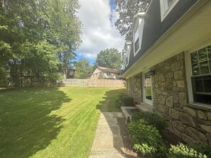 A residential property with a stone exterior, a well-maintained lawn, and a wooden fence.