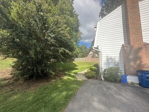 Una propiedad residencial con entrada pavimentada, un árbol grande y una chimenea de ladrillo.