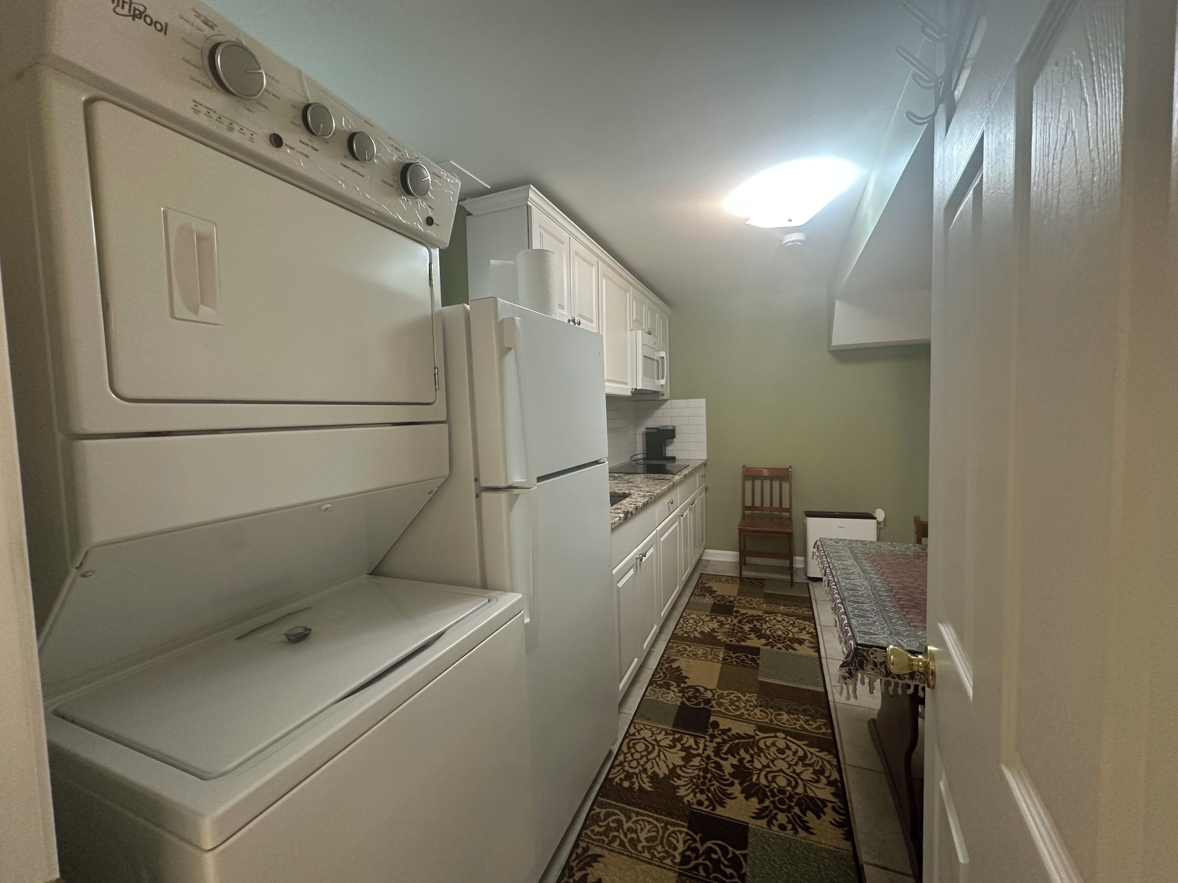 A compact kitchen with a washer-dryer unit, a refrigerator, and a microwave.