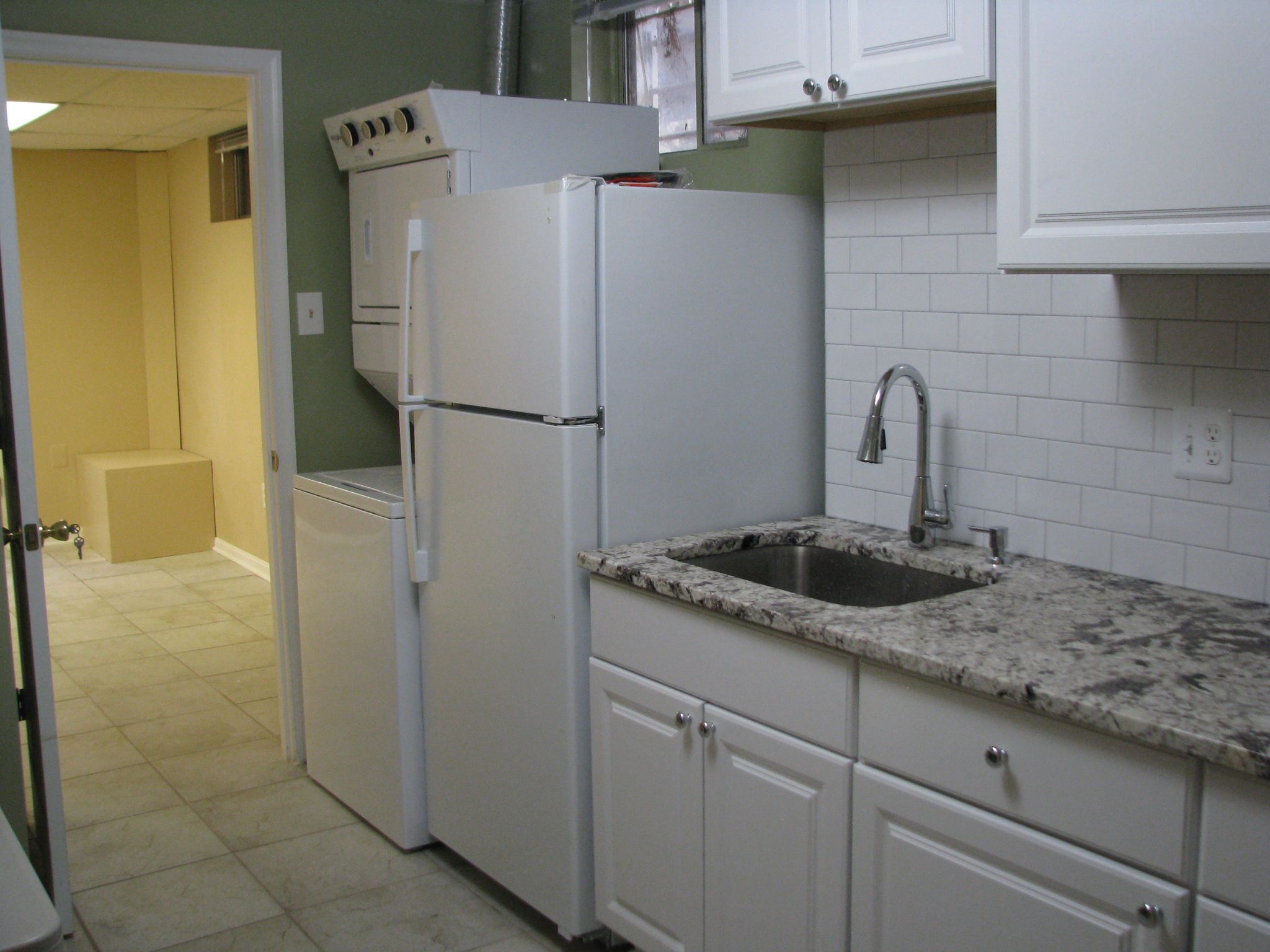 A kitchen with white cabinets, a built-in sink, and a refrigerator.
