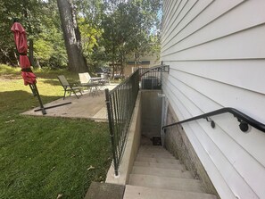 A residential outdoor area with a concrete staircase leading to a deck, surrounded by a metal railing.