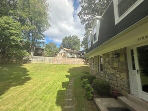 A residential property with a stone facade, a well-maintained lawn, and a wooden fence.