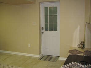 A room with a white door, a patterned rug, and a small table with a decorative item.