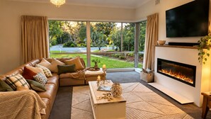 A modern living room with a sofa, coffee table, fireplace, and a TV.