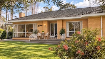 Ett bostadshus med en inglasad veranda, en fasad av tegel och en välskött gräsmatta.