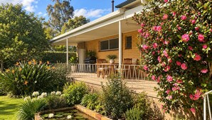 Un patio techado con una parrilla, asientos y un jardín con nenúfares y plantas en flor.
