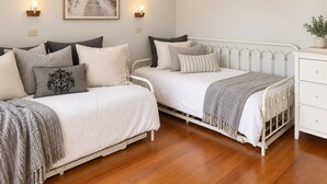 Un dormitorio con dos camas, una mesita de noche, un aparador y una lámpara fijada en la pared.