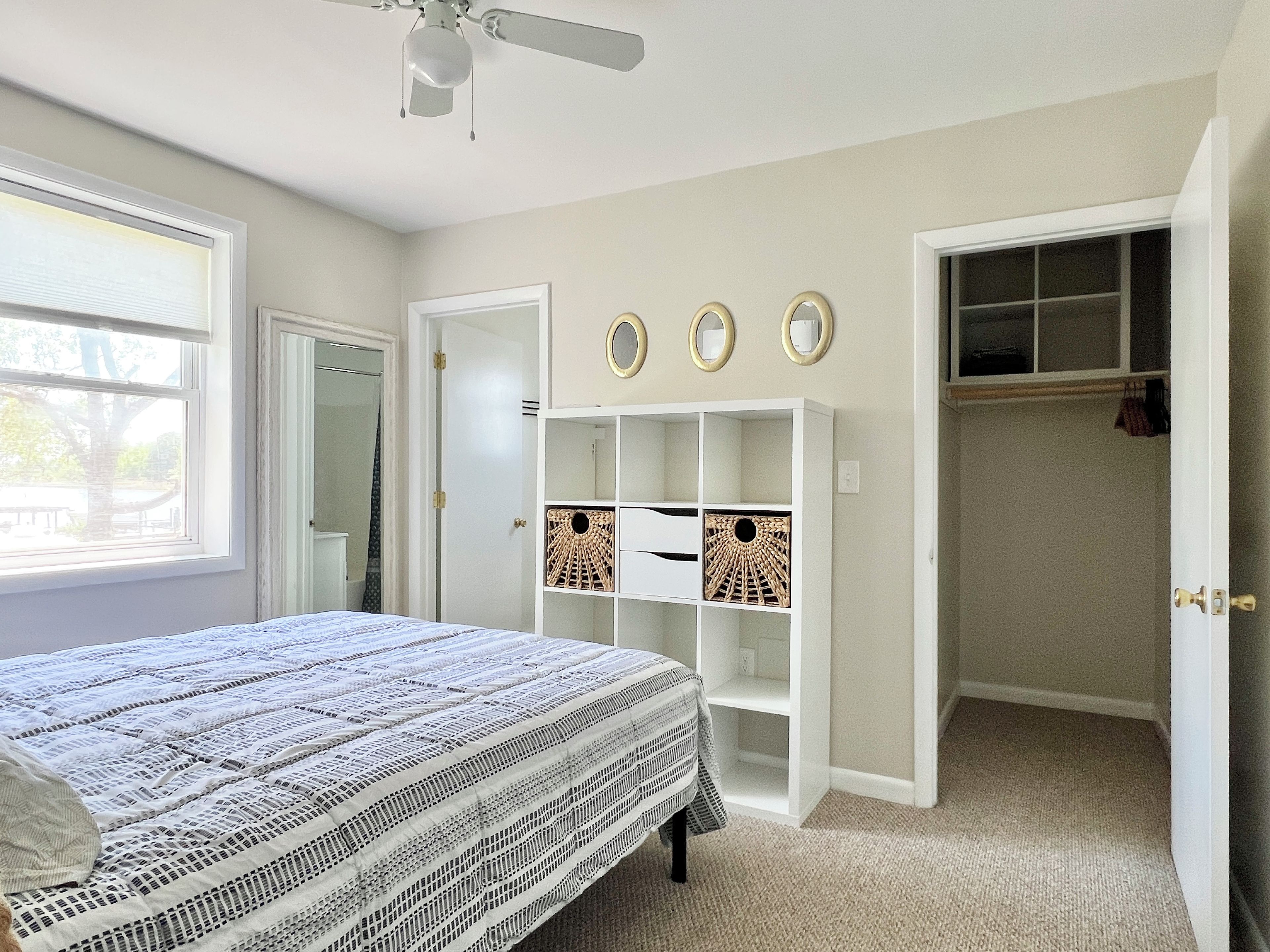 A bedroom with a bed, a ceiling fan, a wardrobe with mirrors, and a door leading to a closet.