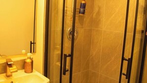 Un baño con ducha de vidrio, lavamanos y espejo.