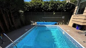 Piscina rectangular con una escalera en un lateral, rodeada por una solana de concreto.