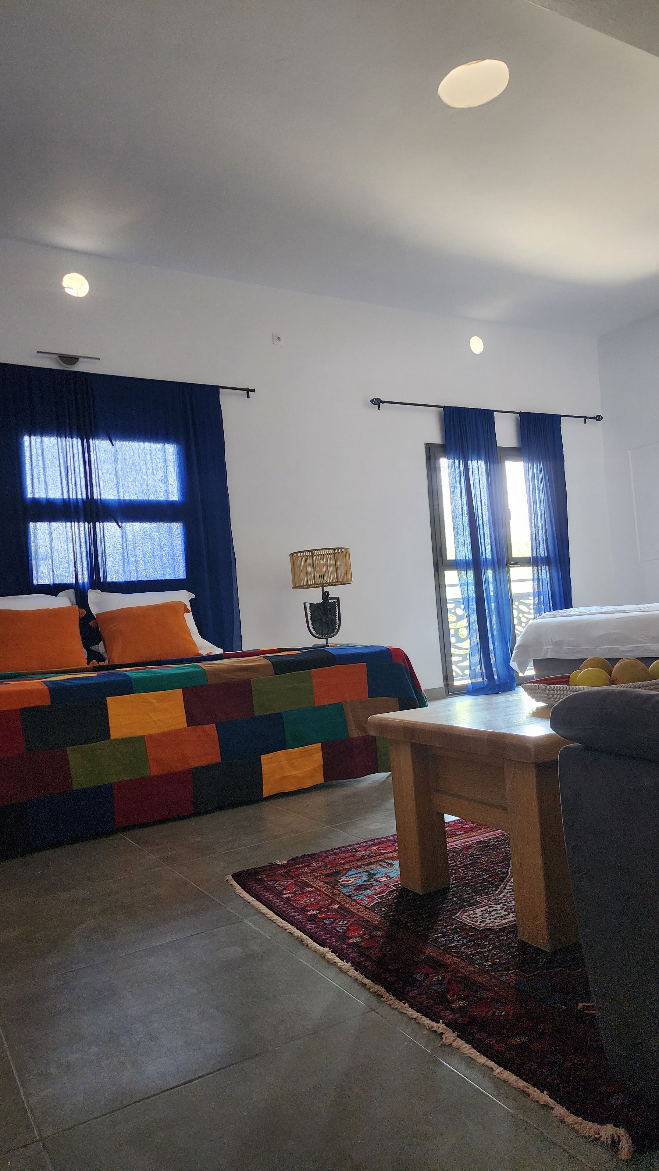 Una camera d'albergo con un letto, un tavolo, una lampada e vista sull'esterno.